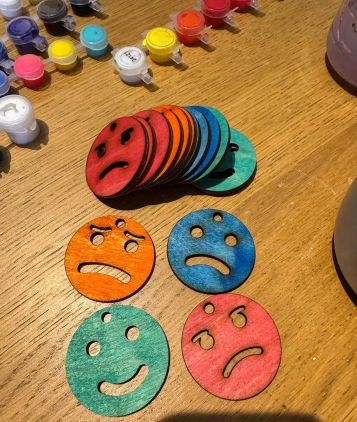 Colorful, circular 3D-printed keyfobs displaying different facial expressions to teach emotional regulation. 