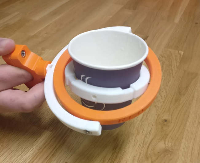 Orange and white 3D-printed stabilizing cup holder holding a paper cup.