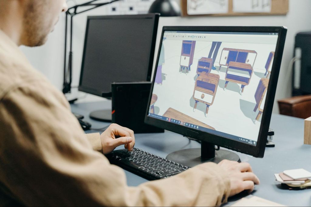 A 3D artist working on a 3D furniture model on a desktop computer monitor