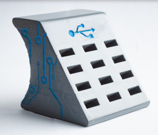 A grey, wedge-shaped 3D printed USB holder featuring decorative blue circuit board patterns