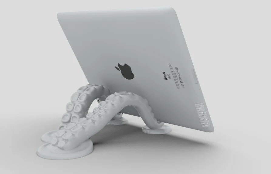 A creative 3D-printed tablet stand shaped like gray octopus tentacles reaching up to support the back of an iPad.