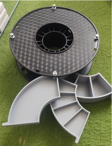 A black, empty 3D printer filament spool repurposed with smooth, semi-circular grey 3D-printed swing-out drawers for storing small hardware.