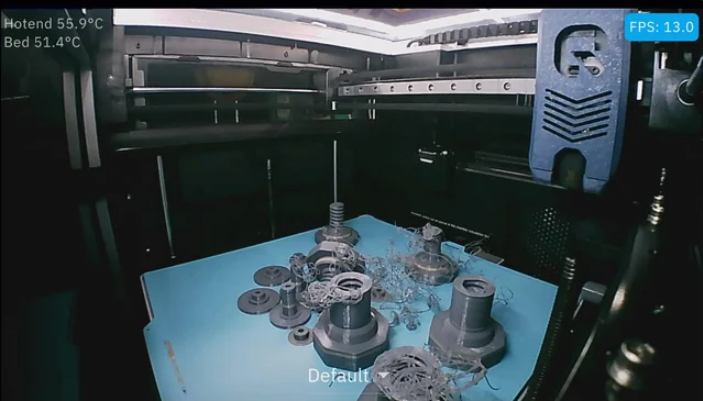 An Octoeverywhere camera feed showing a massive grey spaghetti print failure scattered across a blue print bed.  