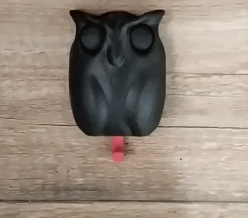 A solid black 3D printed owl-shaped wall key holder featuring a red hook hanging from the bottom for easy key storage.