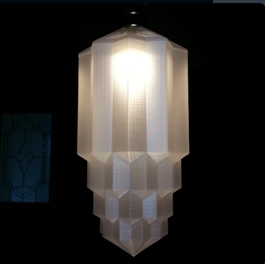 A 3D printed translucent Art Deco style lampshade with a symmetrical, tiered geometric design illuminated from within