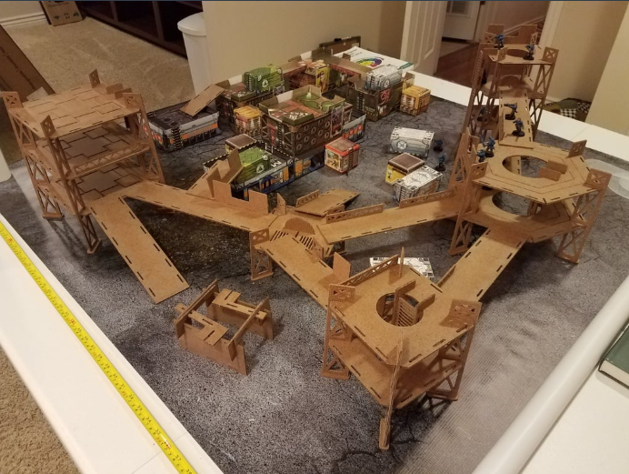 A large, detailed tabletop gaming terrain setup made of laser-cut or 3D printed structures.