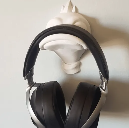 white 3D printed wall hanger shaped like a duck's head, securely holding a pair of large black over-ear headphones.