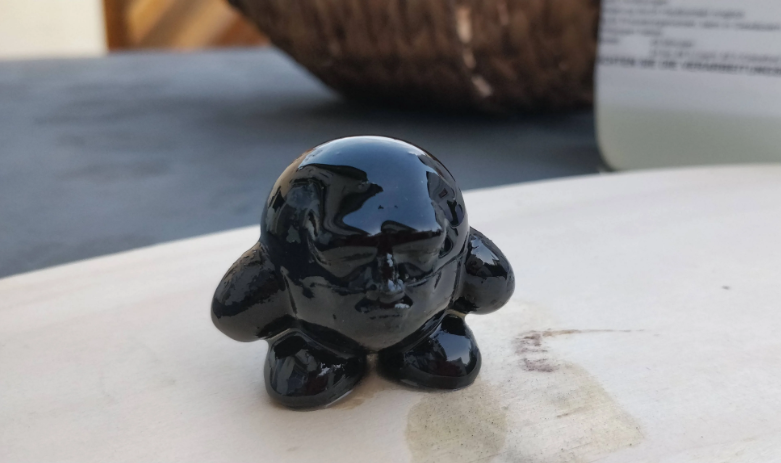 A small, glossy black 3D-printed figure showcasing a smooth, shiny resin-coated finish.