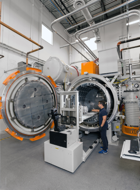 An engineer operating a large industrial hybrid 3D printer capable of multi-material additive manufacturing, featuring an open circular chamber