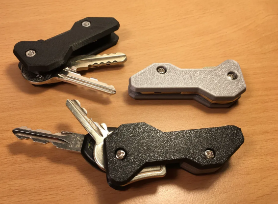 Three 3D-printed single-hand key organizers in black and silver, demonstrating how the keys safely swivel out for easy access.