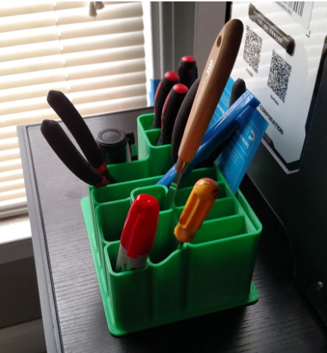A comprehensive grey and black 3D-printed Gridfinity storage unit featuring stacked drawers with bright orange handles and customizable drop-in tray inserts.