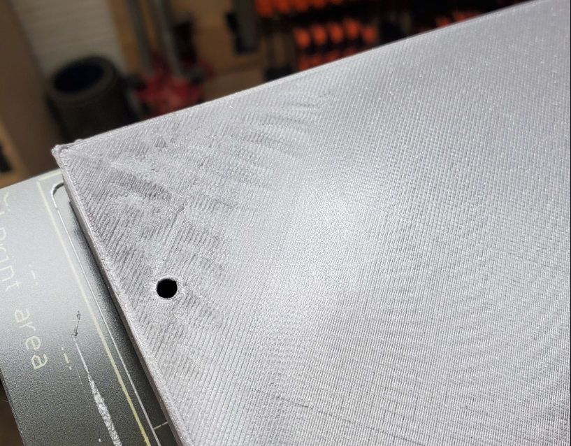 A close-up of a large grey 3D printed part displaying a noticeably rough and uneven top layer, highlighting the need for troubleshooting.