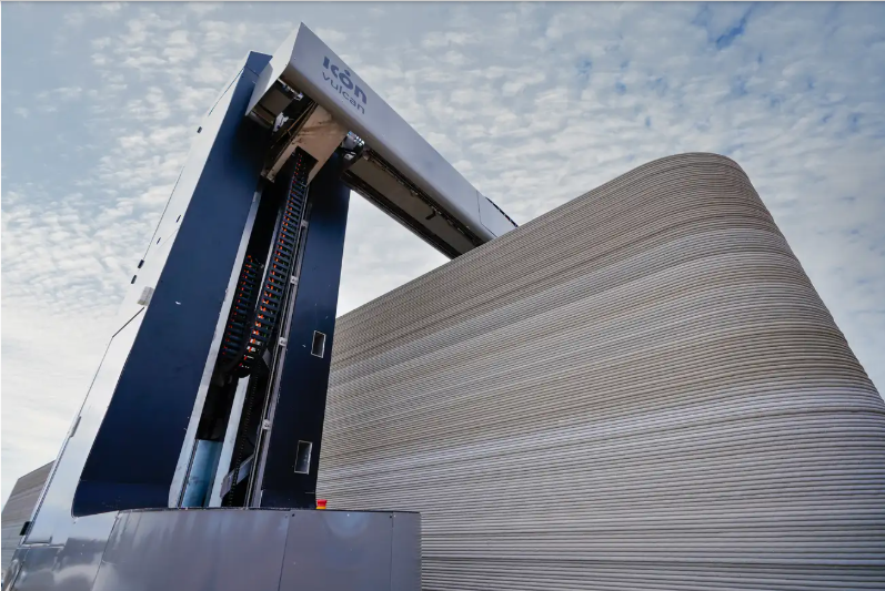 A massive robotic construction 3D printer extruding thick layers of grey concrete to build the walls of a residential house