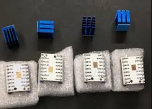 Four small TMC silent stepper motor driver circuit boards with blue heatsinks