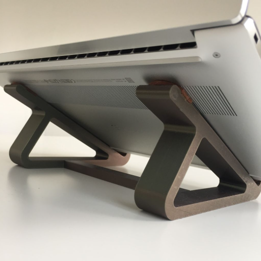 A silver laptop resting on a fixed 3D-printed laptop stand designed to elevate the screen, alleviate neck strain, and improve device ventilation.
