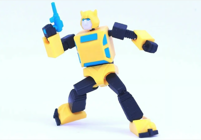 A 3D printed yellow and blue articulated G1 Bumblebee action figure posing with a small blue blaster on a white surface.