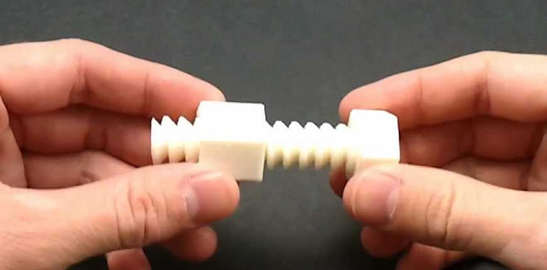 Hands demonstrating how the helical ridges of a white 3D printed screw and nut interlock together.
