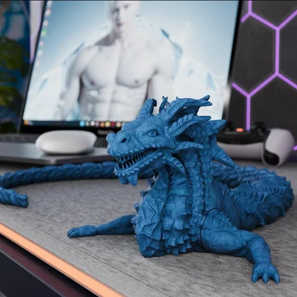 An articulated, flexible blue 3D-printed dragon model resting on a desk mat.  