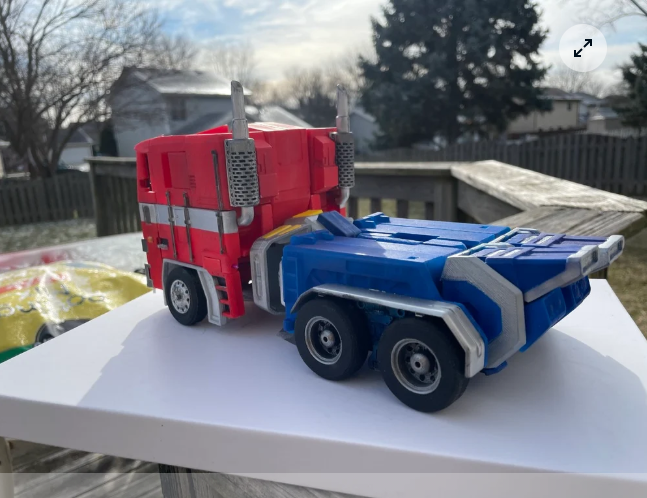 A 3D printed Masterpiece Optimus Prime model fully transformed into its recognizable red, blue, and silver semi-truck vehicle mode.