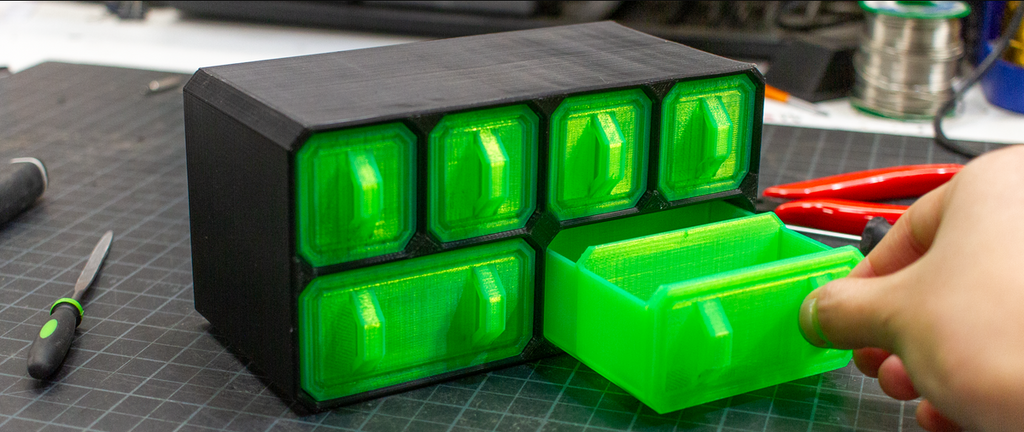 3D printed modular storage drawers showcasing the naturally glossy and durable finish of green and black PETG filament.