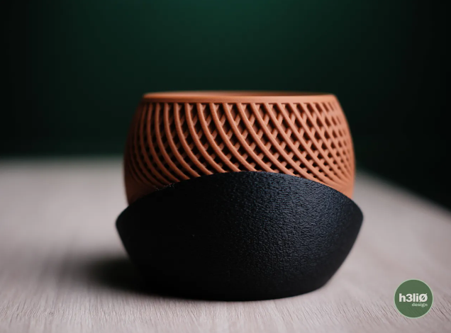 A modern 3D printed planter pot made of wood PLA with a textured geometric pattern, resting inside a smooth black rounded base.