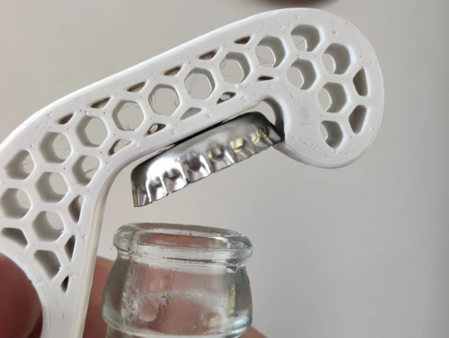 White 3D-printed honeycomb bottle opener removing a metal cap
