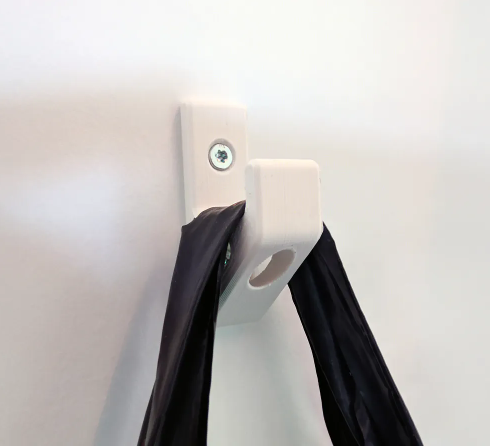 A sturdy, white 3D printed wall hook secured with two metal screws, shown holding a thick black strap.