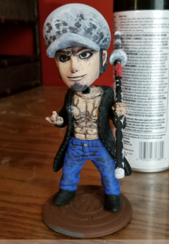 A custom, hand-painted 3D printed bobblehead figure of Trafalgar Law from One Piece holding his long nodachi sword.