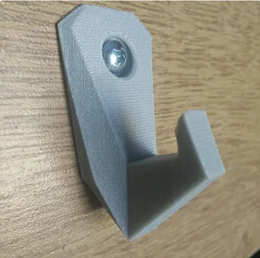A sturdy, grey 3D printed Strong Arm hook securely fastened to a wooden surface with a single metal screw