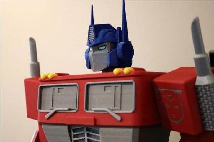 A detailed, multi-material 3D printed Optimus Prime bust showcasing rich red, blue, and silver colors printed without the need for paint.