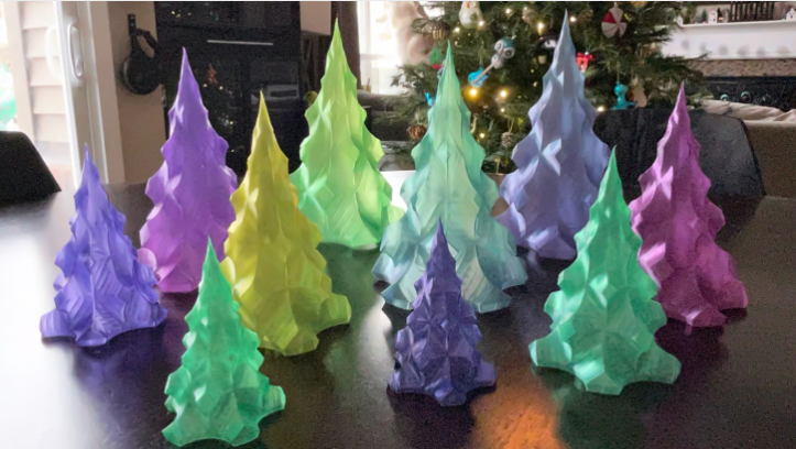 A colorful collection of 3D-printed Christmas trees made using vase mode, featuring festive shades of purple, green, yellow, and blue.