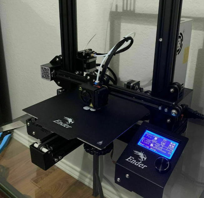 A refurbished Creality Ender-3 V2 FDM 3D printer set up on a glass table. 