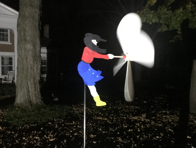 A 3D-printed wind spinner shaped like a girl holding an umbrella, displayed outdoors at night.