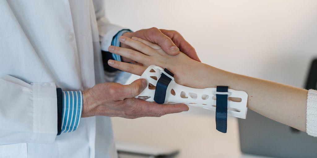 A doctor carefully fitting a custom, white, highly-breathable 3D printed medical cast onto a patient's arm
