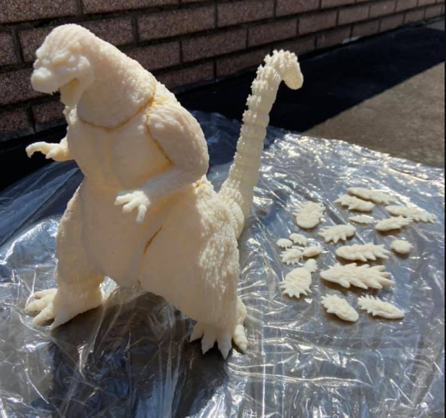 A white, unpainted 3D printed model of the 1995 Mechagodzilla standing next to its freshly printed detached dorsal plates.