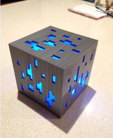 A cube-shaped 3D printed Minecraft Diamond Ore lamp emitting a gentle glow