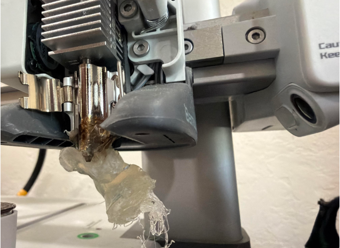 A large blob of melted plastic stuck to a 3D printer hotend, illustrating the results of a severe clog and temperature issues.