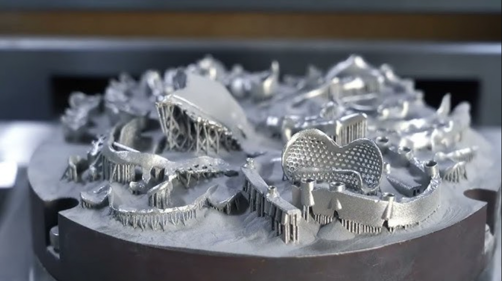 A close-up of a metal 3D printer's circular build plate filled with various freshly printed, intricate titanium components and their attached support structures