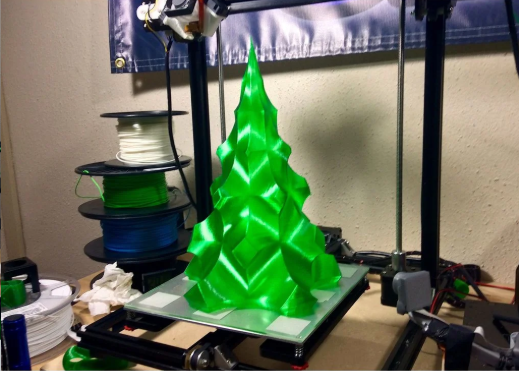 A bright green, geometric 3D printed Christmas tree sitting on the build plate of a 3D printer