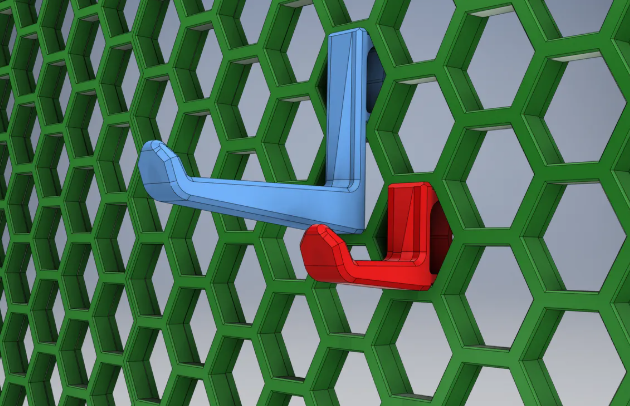 A red and a blue 3D printed pegboard hook inserted directly into a green hexagonal pegboard wall system without the need for screws or fasteners.
