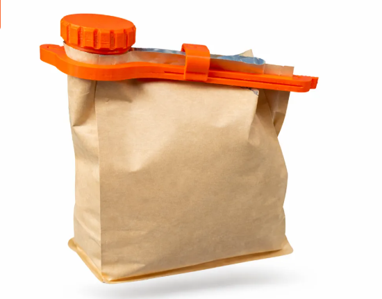 Orange 3D printed bag seal clip with screw cap attached to a paper coffee bag