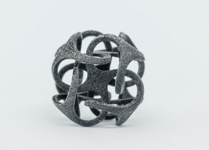 An intricate, dark grey 3D printed geometric sphere demonstrating the flexibility, detail, and surface finish possible with polypropylene filament