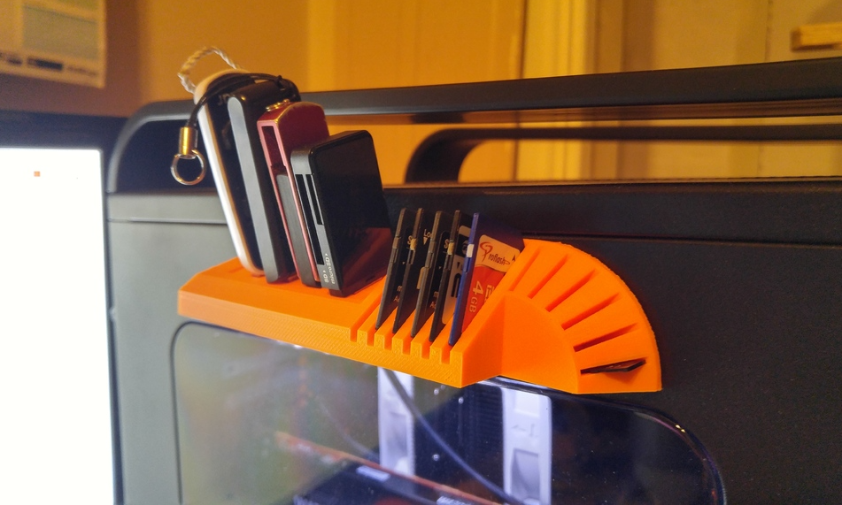 An orange, semi-circular 3D printed USB and SD card holder