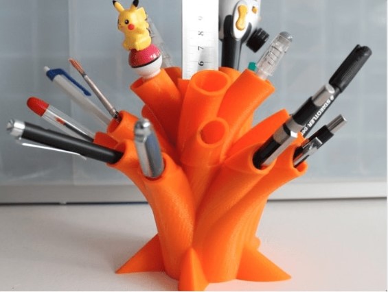 A vibrant orange 3D printed tree-shaped desk organizer holding multiple pens, pencils, and markers